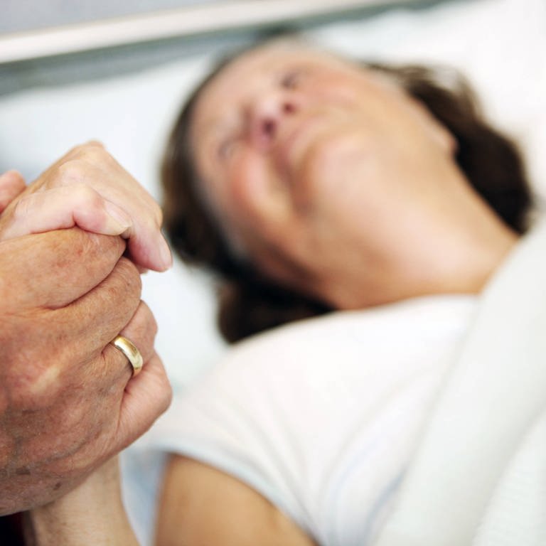 Hand einer alten Frau im Krankenbett wird gehalten (Foto: IMAGO, imago/imagebroker)