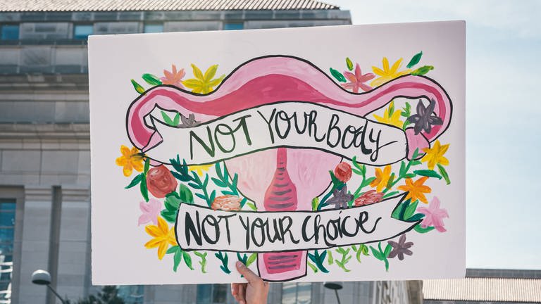 Eine Frau, die ein Schild hält, auf dem steht, dass nicht dein Körper, nicht deine Wahl (Foto: unsplash/Gayatri Malhotra)