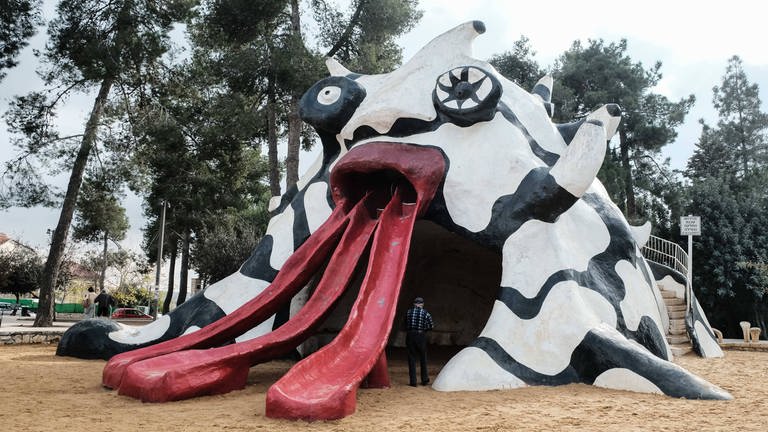 A triple tongued mifletzet, Hebrew for monster, slide, stands in the Rabinowitz Garden at a busy corner in the Kiryat Hayovel neighborhood. Better known as Monster Park, it consists of a sandy plot on which the sculpture is situated as well as a green space with mature trees and wooden picnic tables. French artist Niki de Saint Phalle created the grotesque and friendly monster in 1972, commissioned by longtime and legendary Jerusalem Mayor, Teddy Kollek, himself a resident of Kiryat Hayovel.  (Foto: IMAGO, imago images / ZUMA Press)