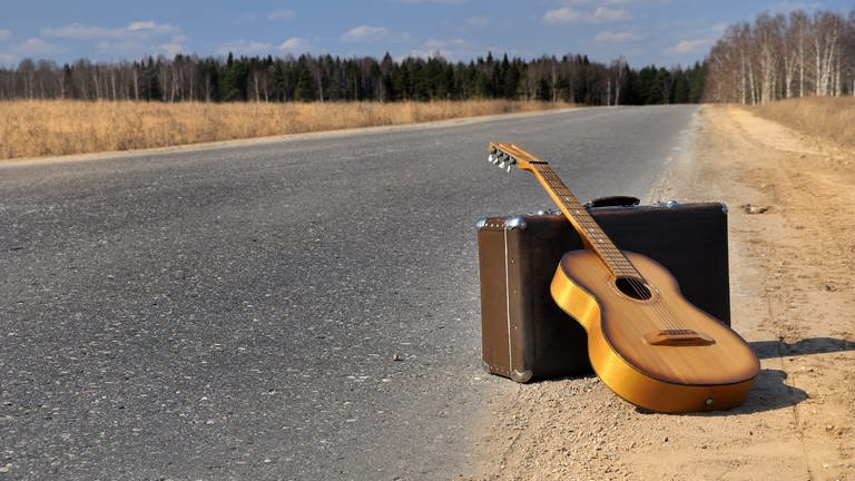 Gitarre und Koffer auf einer Straße (Foto: IMAGO, IMAGO / agefotostock)