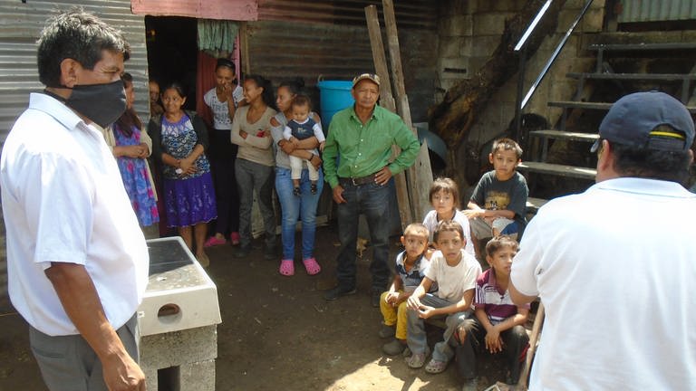Hector Puac (links) und Herber Santos (rechts) zeigen den Familie, den Kochherd richtig aufzubauen und zu warten. (Foto: Pressestelle, Andreas Boueke)