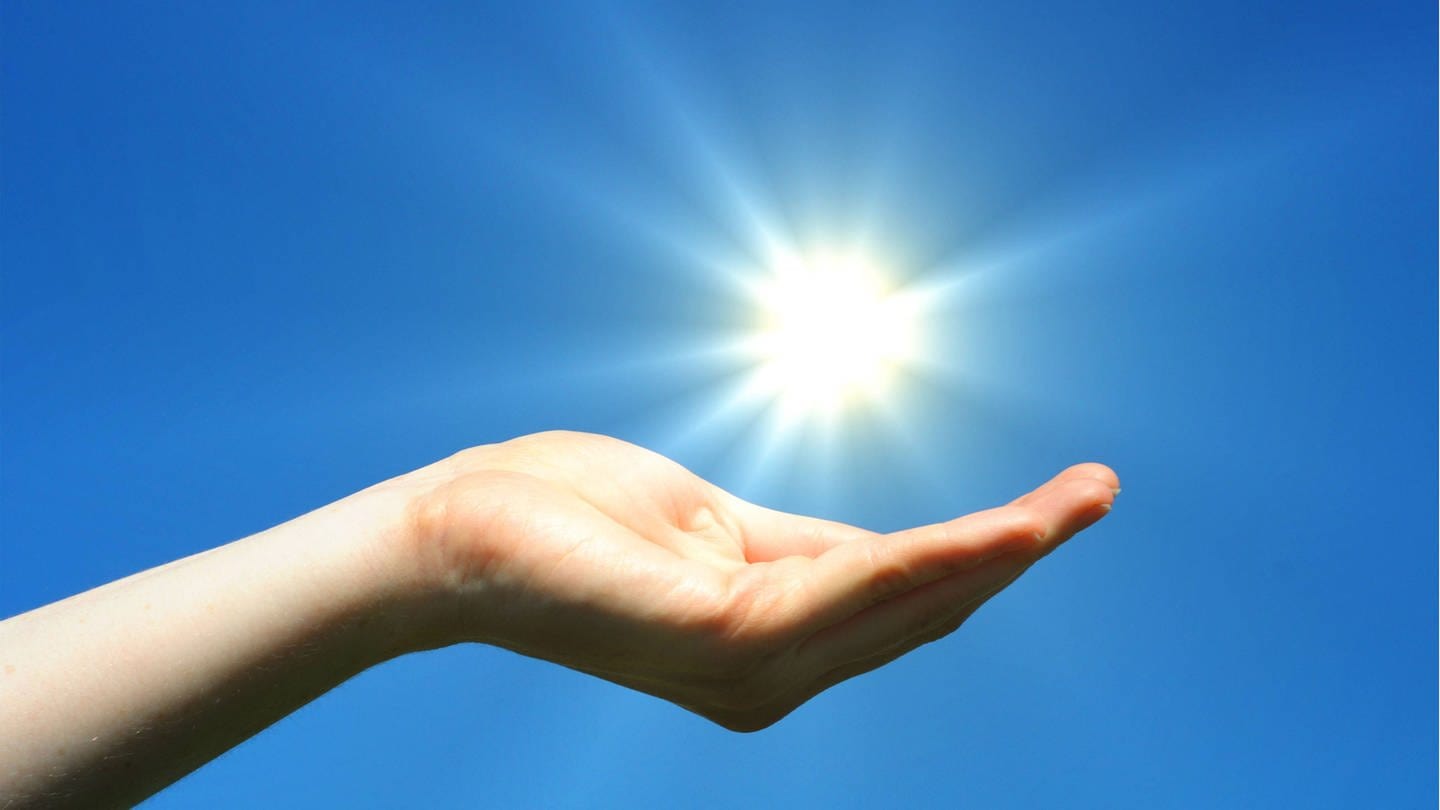 Eine geöffnete Hand unter einer strahlenden Sonne (Foto: IMAGO, imago images/YAY Images/gunnar3000 1108264)