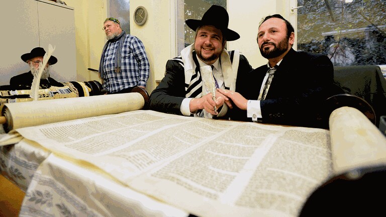 Rabbiner David Geballe (links) legt seine Hand auf die des Thoraschreiber Steve Karro (rechts), der die Gänsefeder führt. (Foto: Hans-Joachim Winckler, Fürther Nachrichten)