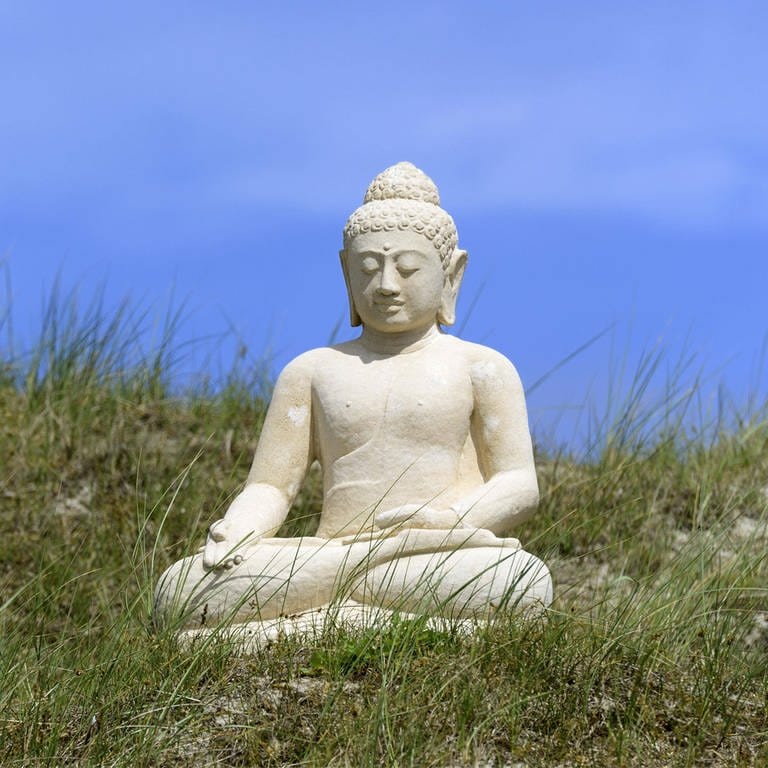 Eine Buddha-Skulptur in der Dünenlandschaft von Norderney