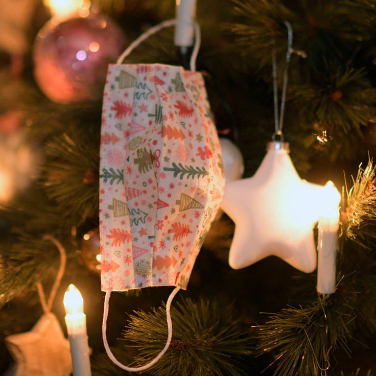 Am Weihnachtsbaum hängt ein Mund-Nasen-Schutz (Foto: IMAGO, imago images/MiS)