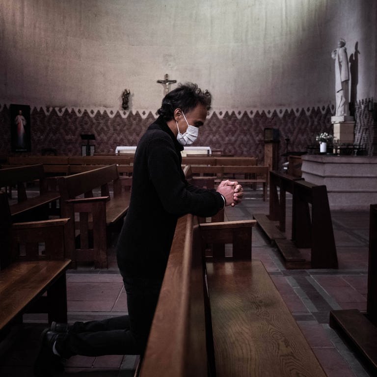 Ein betender Mann mit einer Atemschutzmaske in einer Kirche (Foto: IMAGO, imago images/IP3press/Alexis Sciard )