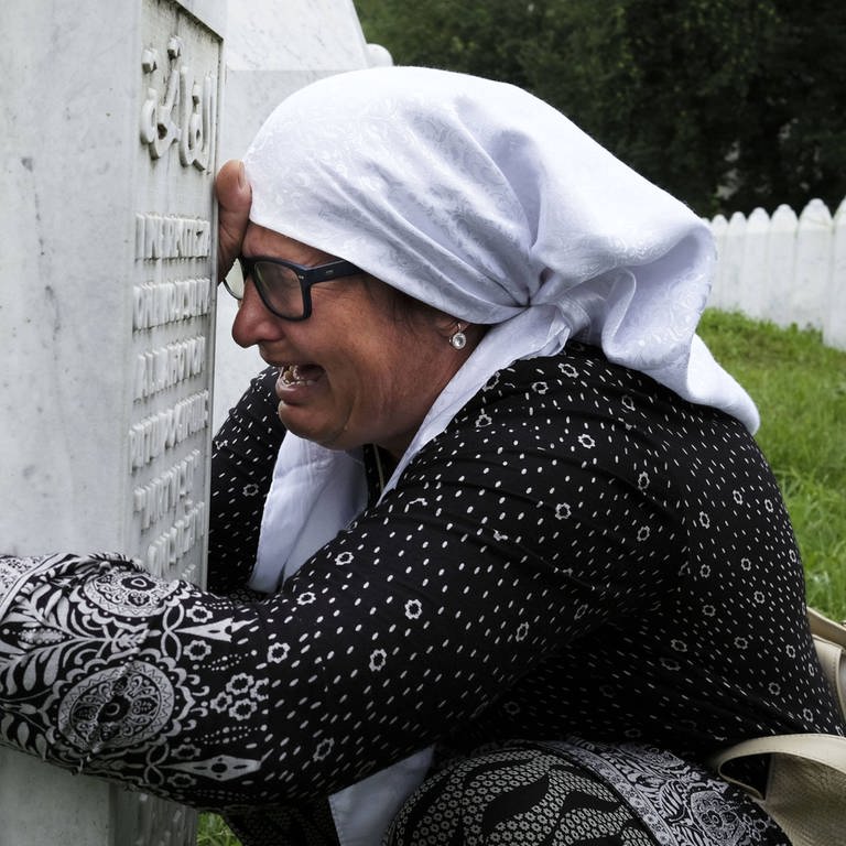 Eine trauernde Frau an einem Grab in Srebrenica