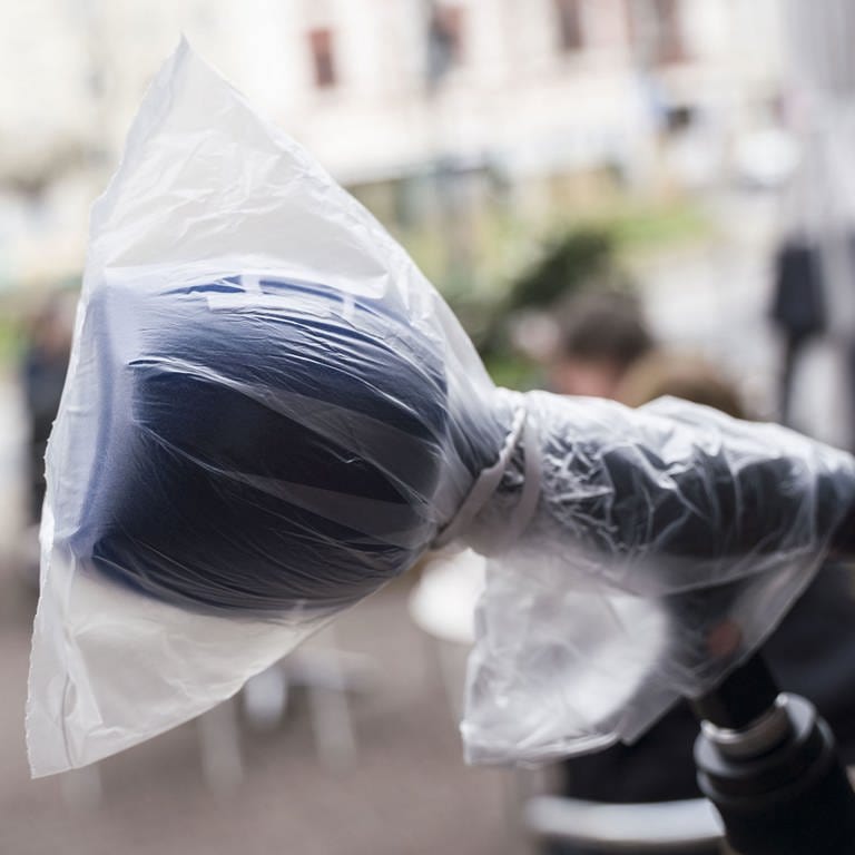 Ein Mikrofon, das mit einer Plastiktüte vor Viren geschützt wird (Foto: picture-alliance / Reportdienste, picture alliance/Frank Rumpenhorst/dpa)