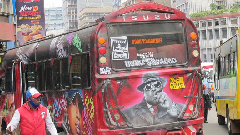 Ein roter Bus, bunt bemahlt fährt duch eine belebte Straße in Nairobi.  (Foto: Antje Diekhans)