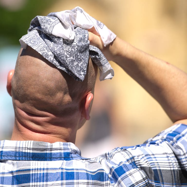 Ein Mann wischt sich mit einem Stofftuch über den Kopf. (Foto: dpa Bildfunk, picture alliance / dpa | Sebastian Kahnert)