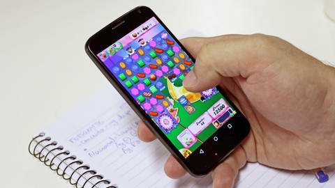 Eine Hand mit einem Smartphone spielt Candy Crush.