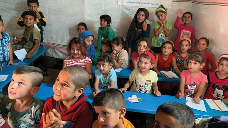 Strahlende und lachende Kinder sitzen in der Zeltschule (Foto: Zeltschule)