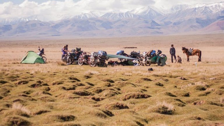 Motorradfahrer haben in der mogolischen Steppe ein Zelt aufgebaut. Im Hintergrund sind Berge zu sehen (Foto: leavinghomefunktion)