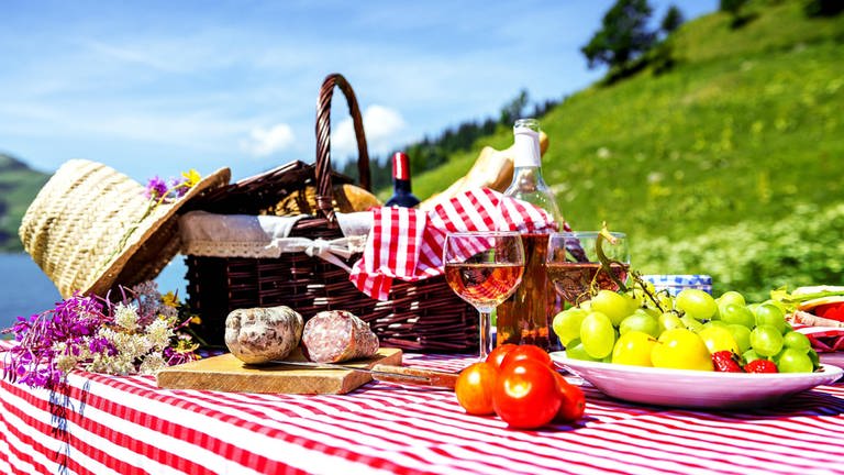 Gedeckter Tisch mit Picknickkorb in Seelandschaft