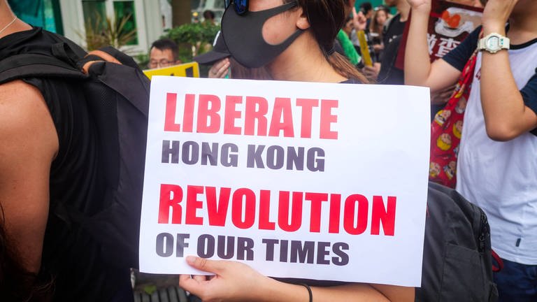 Proteste in Hongkong. Eine Frau trägt ein Plakat mit der Aufschrift "Liberate Hongkong. Revolution of our times" (Foto: IMAGO, imago images / UPI Photo / Foto: THOMAS MARESCA)