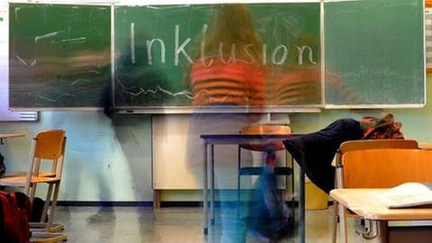 Das Wort Inklusion steht an einer Schultafel, Schüler betreten den Klassenraum. (Foto: SWR, SWR -)