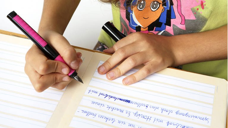 Schulmädchen schreibt mit einem Füller in ein Heft (Foto: IMAGO, imago stock&people / imago/CHROMORANGE)