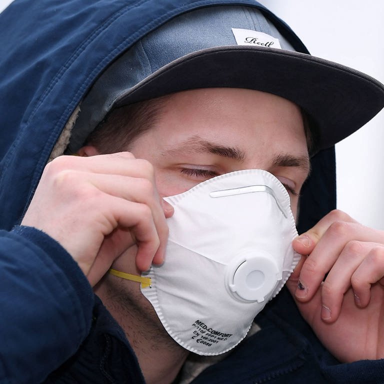 Ein Mann mit einer Schutzmaske vor einer Apotheke (Foto: IMAGO, imago images / ULMER Pressebildagentur / Markus Ulmer)