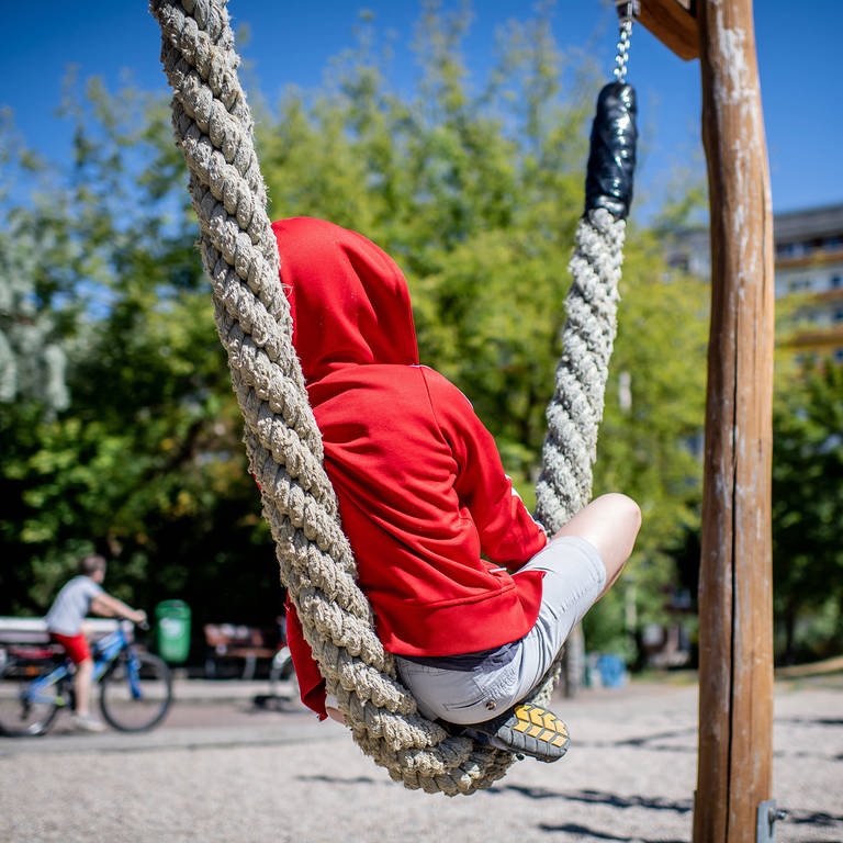 Ein Kind sitzt auf einem Spielplatz (Foto: IMAGO, Thomas Eisenhuth)