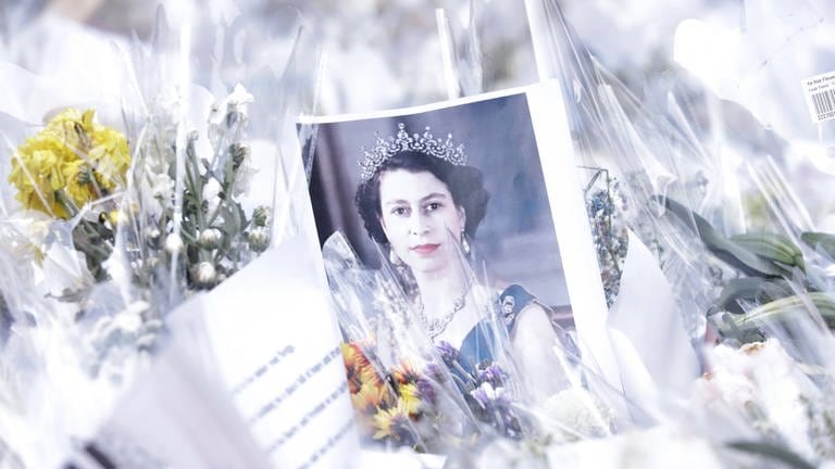 Ein Portät der Queen in jungen Jahren in einem Blumenmeer