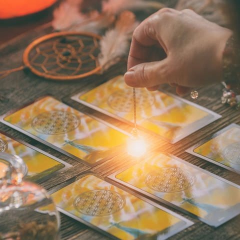 Fortune teller holding a pendulum over tarot cards Symbolfoto (Foto: IMAGO, Agefotostock)