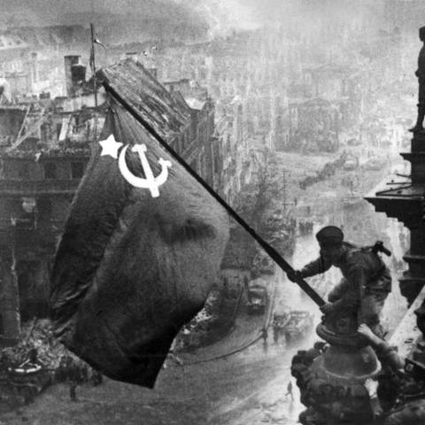 Der sowjetische Soldat Militon Kantarija aus Georgien hißt am 2. Mai 1945 die sowjetische Flagge auf dem Berliner Reichstag.  (Foto: picture-alliance / Reportdienste, picture-alliance / dpa | tass)