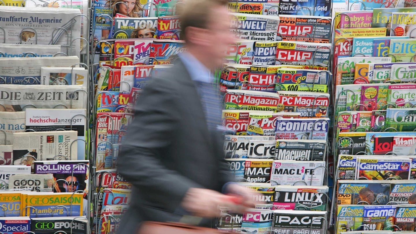 Ein Mann im Anzug und mit einer braunen Aktentasche in der Hand geht am 08.07.2008 in Stuttgart an einem Zeitungs- und Zeitschriftenständer vorbei. (Foto: picture-alliance / Reportdienste, Foto: Uwe Anspach dpa/ lsw)
