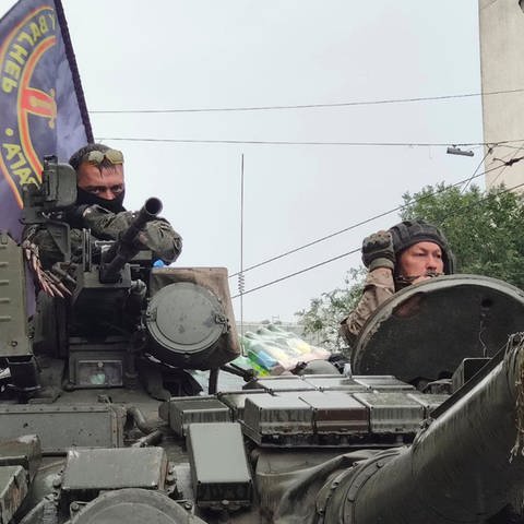 Kämpfer sitzen in einem Panzer mit einer Flagge der Wagner-Gruppe