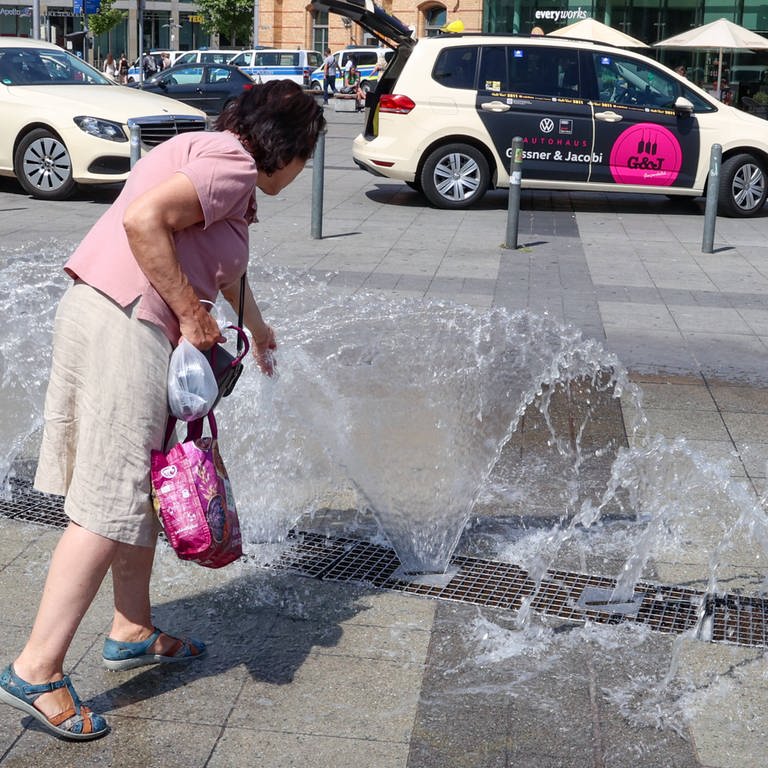 Eine Passantin kühlt sich am Brunnen vor dem Hauptbahnhof Hannover ab (Foto: IMAGO, IMAGO / localpic)