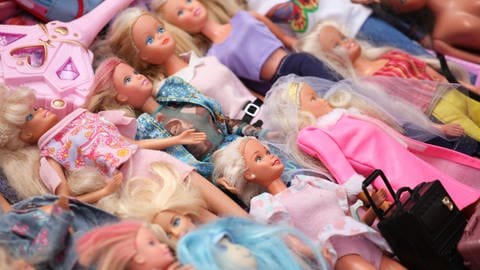 Mehrere gebrauchte Plastikpuppen in der Art sogenannter Barbies liegen zum Verkauf an einem Stand auf einem Flohmarkt