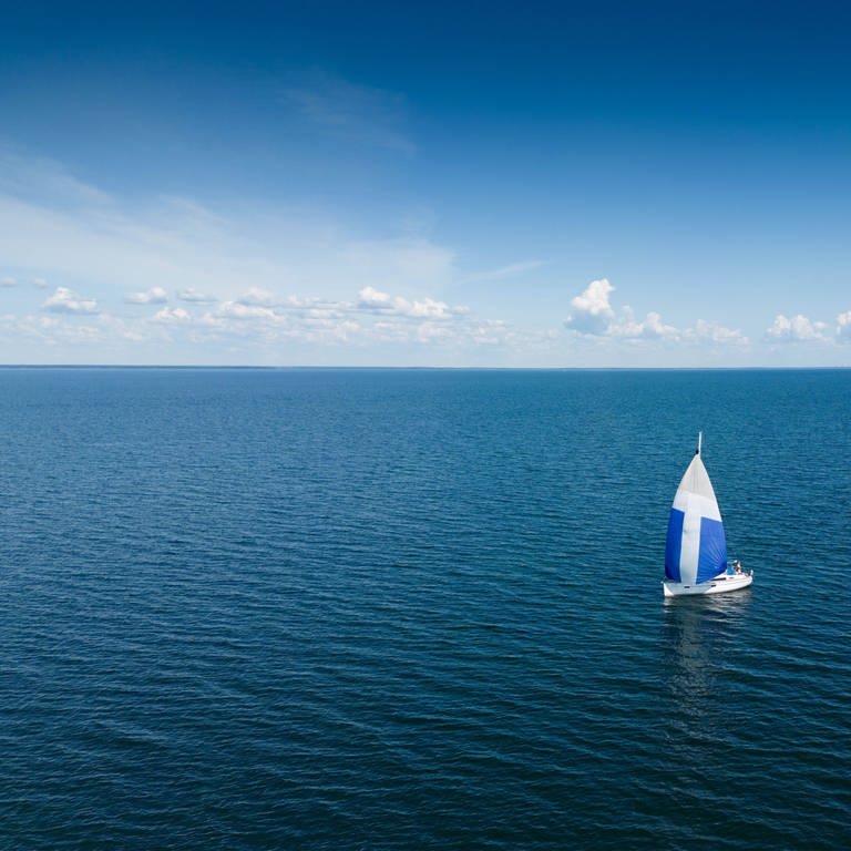 Segelboot Ein Segelboot fährt mit einem blau-weißen Gennaker-Segel vor der schwedischen Insel Öland auf der Ostsee. Köping Öland Schweden
