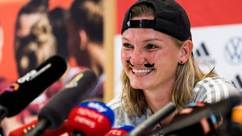 Alexandra Popp mit Schnurrbart bei einer Pressekonferenz (Foto: IMAGO, IMAGO/Beautiful Sports)