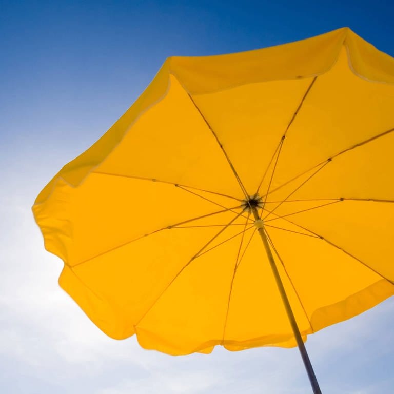 A yellow sunshade against a deep blue sky. Symbolfoto (Foto: IMAGO, Design Pics)