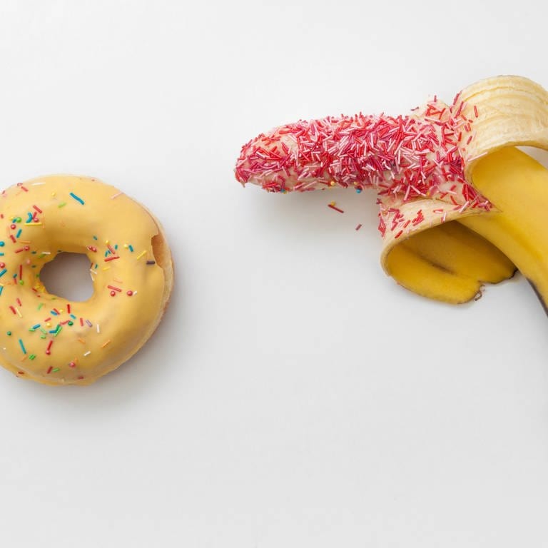 Eine Banane und ein Donut liegen nebeneinander. Symbolfoto für das Buch "Porno"  (Foto: IMAGO, IMAGO / Pond5 Images)