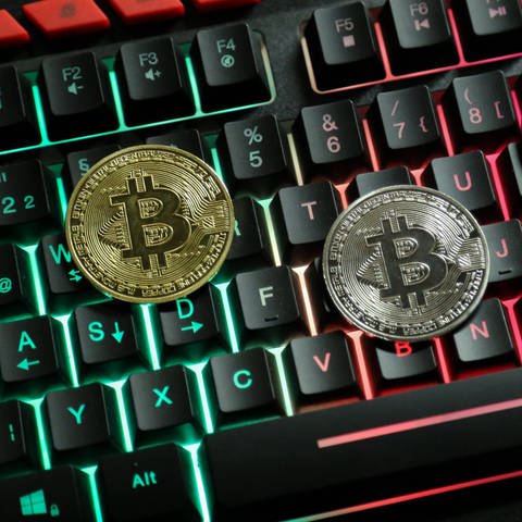 Geldmünzen mit einen B in der Mitte liegen auf einer Computertastatur (Foto: IMAGO, IMAGO / Daniel Scharinger)
