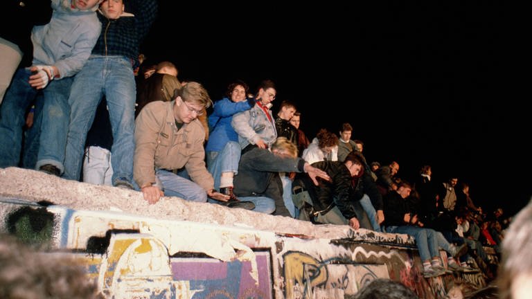 Menschen klettern auf die Mauer. Berlin, 09.11.1989