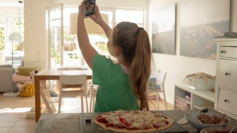 Mädchen fotografiert sich mit Pizza