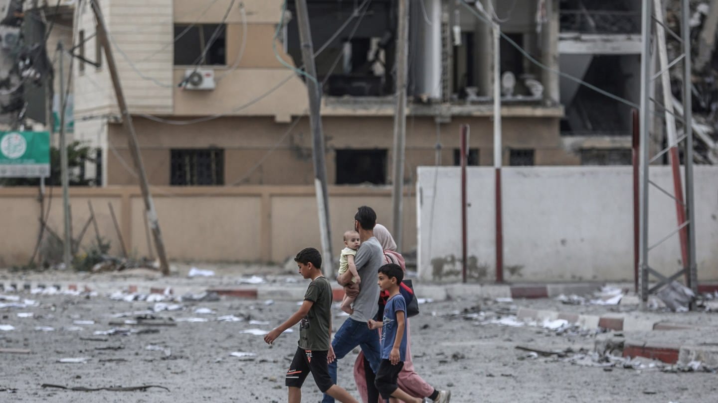 Eine palästinensische Familie geht nach einem israelischen Luftangriff an einem zerstörten Gebäude vorbei. (Foto: dpa Bildfunk, picture alliance/dpa | Mohammed Talatene)