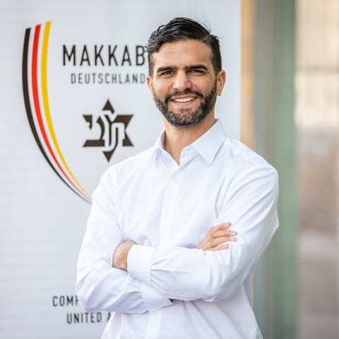 Alon Meyer, Präsident von Makkabi Deutschland, steht vor dem Logo. (Foto: dpa Bildfunk, picture alliance/dpa/MAKKABI Deutschland e. V. | .)