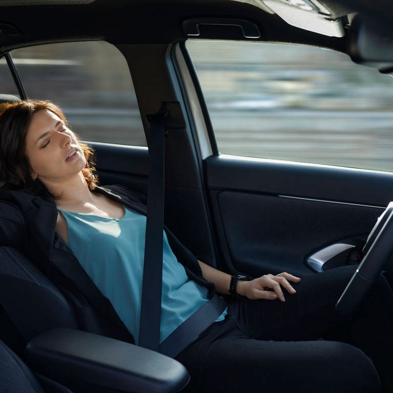 Tired businesswoman sleeping in autonomous driverless car model released, ZEDF04335 (Foto: IMAGO, Westend61)