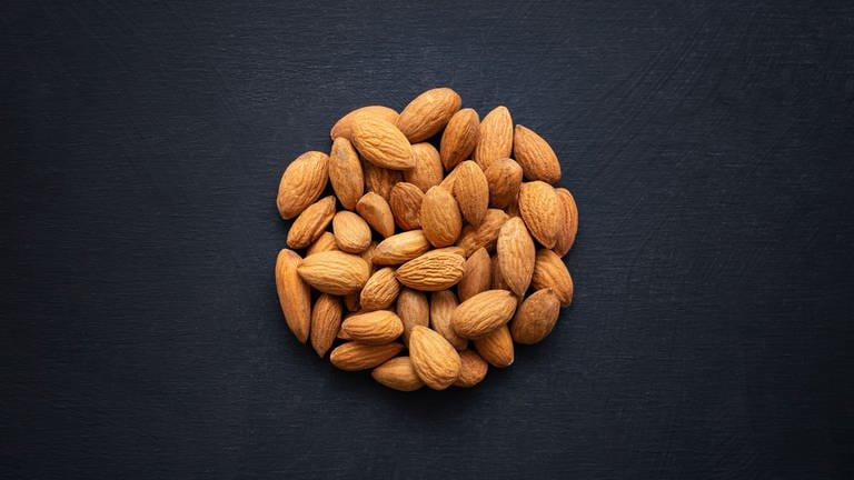 A top view of almonds shaped as a circle on a black background (Foto: IMAGO, Wirestock)