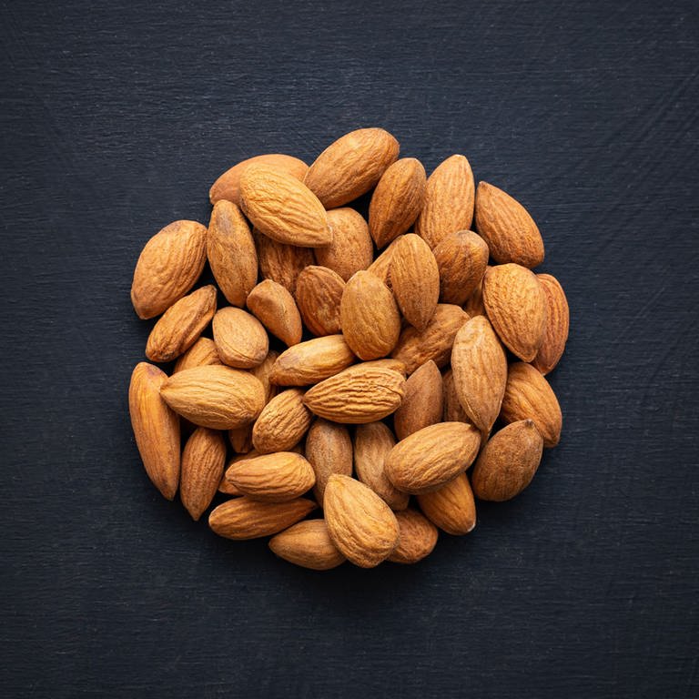 A top view of almonds shaped as a circle on a black background