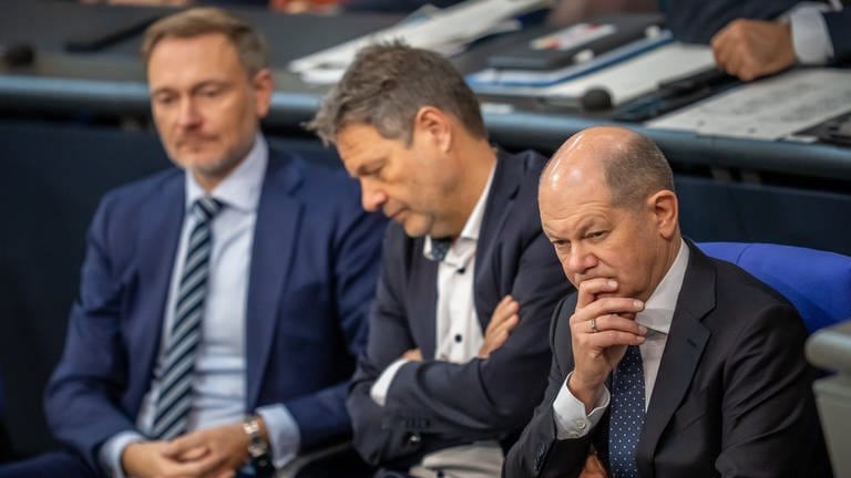 Bundeskanzler Olaf Scholz (SPD, r), verfolgt neben Robert Habeck (Bündnis 90Die Grünen, M), Bundesminister für Wirtschaft und Klimaschutz, und Christian Lindner (FDP), Bundesminister der Finanzen, die Debatte nach einer Regierungserklärung zur Haushaltslage im Bundestag.