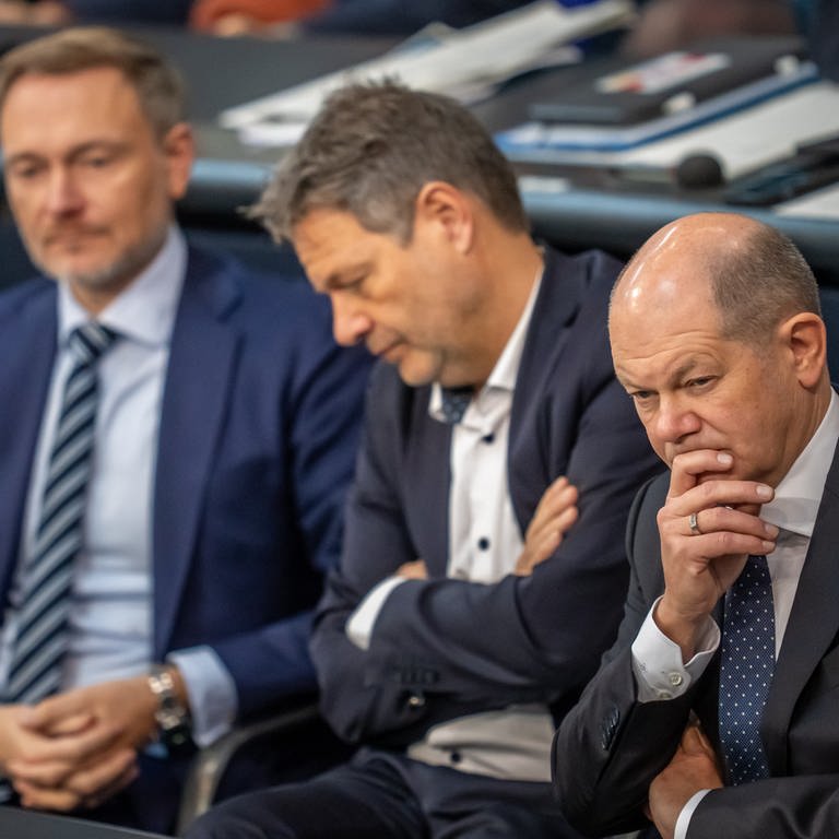 Bundeskanzler Olaf Scholz (SPD, r), verfolgt neben Robert Habeck (Bündnis 90Die Grünen, M), Bundesminister für Wirtschaft und Klimaschutz, und Christian Lindner (FDP), Bundesminister der Finanzen, die Debatte nach einer Regierungserklärung zur Haushaltslage im Bundestag.