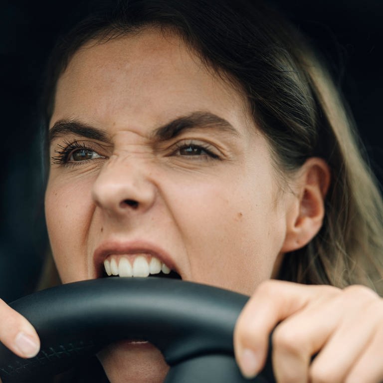 Close-up of angry woman biting steering wheel while while sitting in car model released (Foto: IMAGO, IMAGO / Westend61)