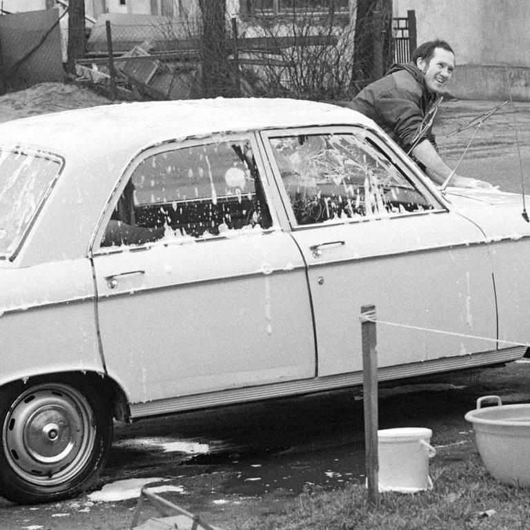 Waschtag Samstag. Junger Mann reinigt sein Auto auf der Strasse mit der Hand, Archivfoto