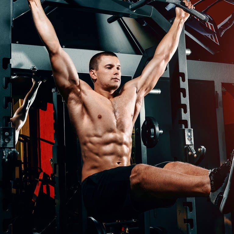 bodybuilder on the bar raises his legs up, exercises on the press in the gym. Symbolfoto