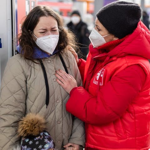 Anna (l), die mit ihren Kindern aus der ukrainischen Hauptstadt Kiew geflohen ist, wird nach ihrer Ankunft am Münchner Hauptbahnhof von einer Mitarbeiterin der Caritas betreut.