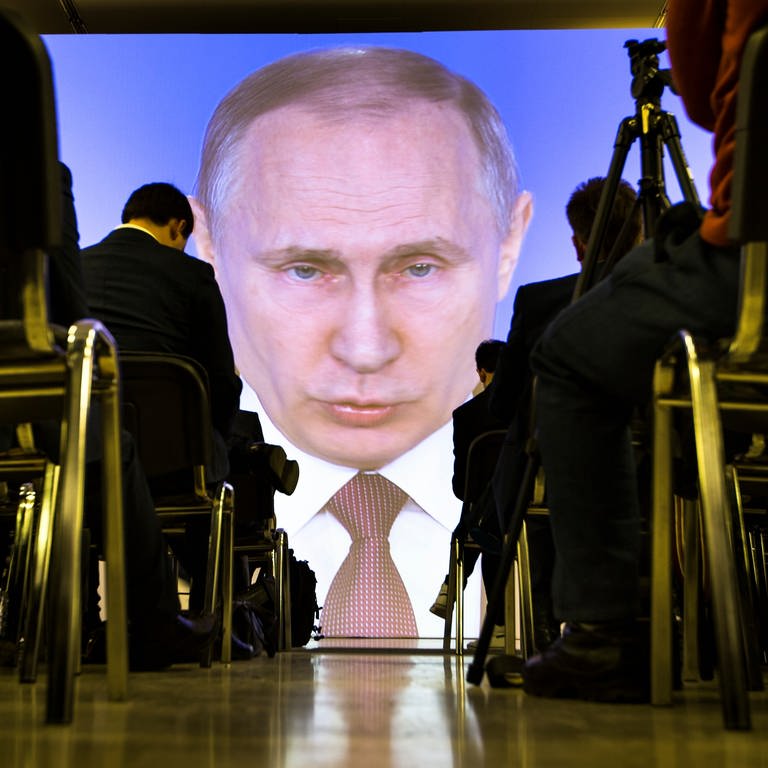 Journalisten verfolgen die Rede von Wladimir Putin, Präsident von Russland, zur Lage der Nation auf einer Videoleinwand.