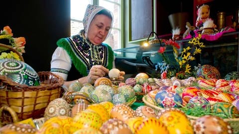 Eine Frau in Schleifer Traacht bemalt sorbische Ostereier im Heimatmuseum Lübbenau 